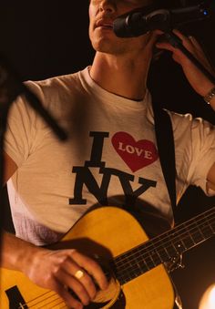 a man holding a guitar and singing into a microphone