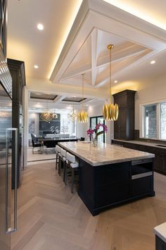 a large kitchen with an island in the middle and two chandeliers hanging from the ceiling