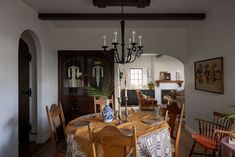 a dining room table with chairs and a chandelier hanging from it's ceiling