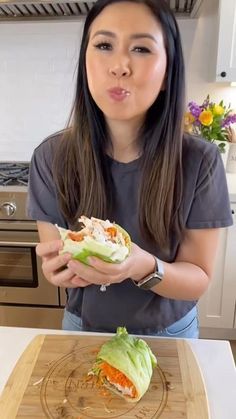 a woman making a face while holding a sandwich in front of her and looking at the camera