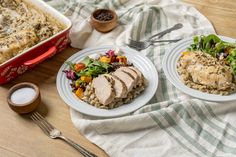 two white plates topped with meat and vegetables next to a casserole dish on a table