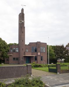 a large brick building with a clock tower in the middle of it's front yard