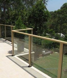 a balcony with glass railings and trees in the background