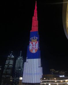 a very tall building with a clock on it's side in front of other buildings