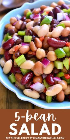 a bowl filled with beans and celery on top of a wooden table next to a