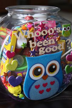 a glass jar filled with lots of colorful items and an owl magnet on the front