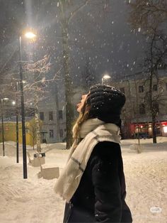 a woman is walking in the snow at night