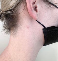 a woman with a small cross tattoo on her left side behind the ear, wearing a black choker