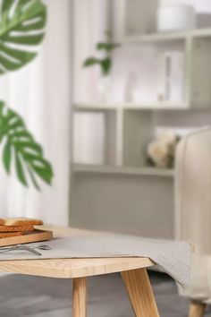 a wooden table with bread on it in front of a white couch and potted plant