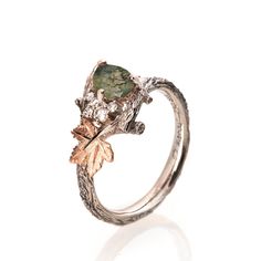 "A handmade 14k twig and leaf ring made in two gold colors and set with a beautiful, natural moss agate and a cluster of quality white diamonds. The grooves in the band are plated with black rhodium which emphasizes the texture. if you prefer not to apply the black rhodium that is fine. I can also use white, rose or yellow gold for the band and the leaves for the same price. The center stone is a 5mmX7mm natural moss agate of high quality. If you are looking at this ring then you are probably looking for something special, something different. The engagement rings I design are made of 100% recycled gold and non-conflict diamonds in high quality. After I am sure you have seen a huge variety of engagement rings I am guessing you get the feeling that they all look pretty much alike, maybe you Nature-inspired Emerald Ring, Moss Ring, Engagement Ring Pear, Leaf Engagement Ring, Green Moss Agate, Diamond Cluster Engagement Ring, Moss Agate Ring, Cluster Engagement Ring, Pear Engagement Ring