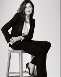 a woman sitting on top of a stool in a black and white photo with her legs crossed