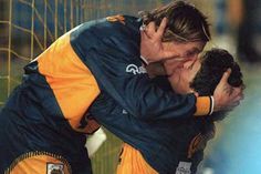 two soccer players hugging each other in front of the net