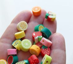 a hand is full of small fruit and vegetable beads on it's thumbnails