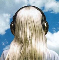 a woman with long blonde hair and headphones on her ears looking up into the sky