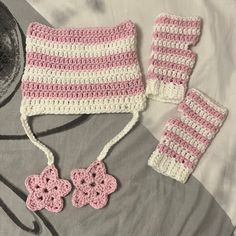 a crocheted hat, mittens and scarf are laying on a bed next to a purse