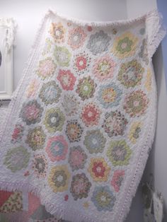 a white crocheted blanket hanging from the side of a wall next to a mirror