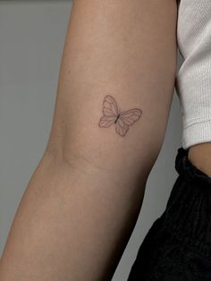 a woman's arm with a small butterfly tattoo on the back of her left arm