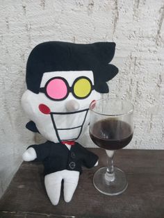 a stuffed doll next to a glass of wine