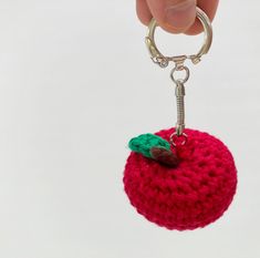 a crocheted apple keychain being held by a hand