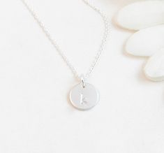 "Minimal Sterling Silver Initial Charm Personalized Necklace: Perfect for layering or alone. All components are sterling silver. One letter of your choice will be hand stamped onto the small disc - choose from 4 fonts. This is a subtle, unoxidized letter with a minimal look. The initial charm is of high quality thickness and 3/8\" in diameter. Available in size 14\" (choker length on most adults), 16\", or 18\" (shown on model). Arrives on a necklace card tucked into an organza gift pouch - read Silver Minimalist Personalized Initial Necklace, Simple Personalized Sterling Silver Charm Necklace, Simple Silver Initials Charm Necklace, Dainty Adjustable Initial Necklace In Sterling Silver, Silver Simple Charm Necklaces With Initials, Simple Silver Charm Necklaces With Initials, Dainty Stamped Silver Charm Necklace, Dainty Silver Stamped Charm Necklace, Simple Silver Hand Stamped Necklaces