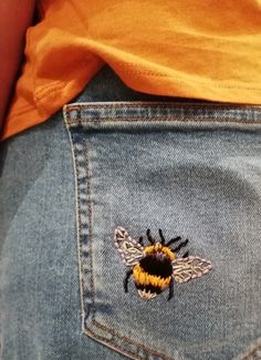 a close up of a person's jeans with a bee embroidered on it