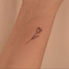 a single flower tattoo on the wrist is shown in black ink and has a thin outline