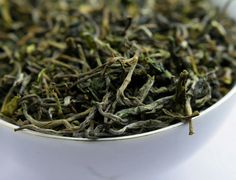 a white bowl filled with green tea on top of a table