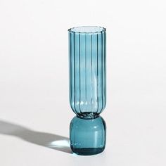 a blue glass vase sitting on top of a white table next to a shadow from the floor