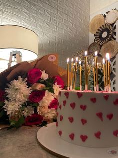 a birthday cake with candles and flowers on a table next to a bouquet of roses