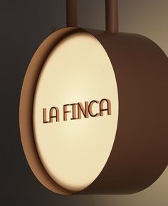 the word la finca is carved in wood on a piece of luggage hanging from a hook