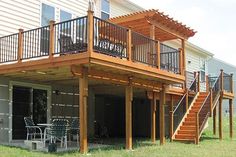 a house with a deck and stairs leading to the upper level balcony, next to a patio