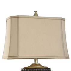 a lamp that is on top of a white table cloth and has a beige shade