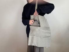 a woman holding a gray bag in her hands