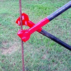 a red fire hydrant sitting on top of a green grass covered field next to a metal pole