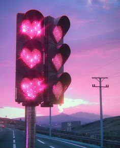 a traffic light with hearts on it is lit up in the evening sky over an empty highway