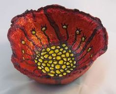 a red bowl with yellow and black designs on the inside is sitting on a white surface