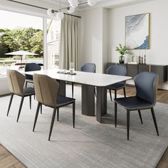 a dining room table with blue chairs and a white rug in front of the window