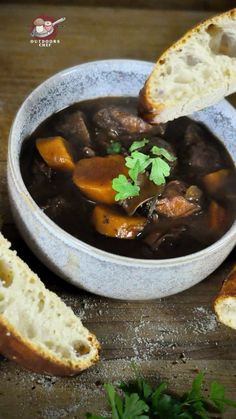 a bowl of stew with bread and parsley on the side, ready to be eaten