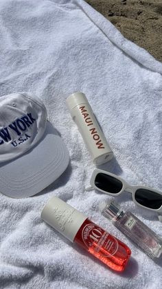 a hat, sunglasses, and other items are laid out on a towel