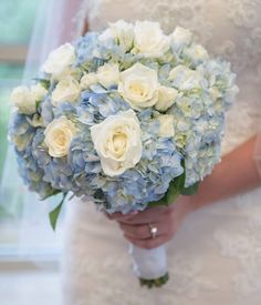 a bride holding a bouquet of white and blue flowers