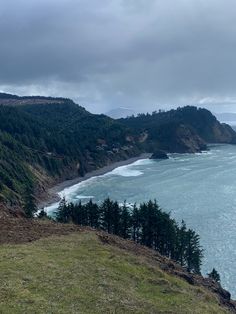 an ocean view from the top of a hill with trees on it and mountains in the background