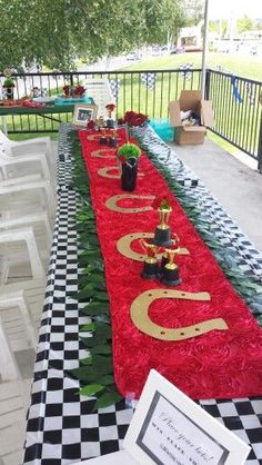 a long table covered in red and green flowers with gold numbers on it, along with black and white checkered flooring