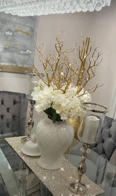 a white vase filled with flowers sitting on top of a table next to a mirror