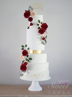 a three tiered white wedding cake with red and pink flowers