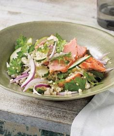 a green bowl filled with meat and veggies on top of a wooden table