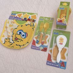 three children's toys including spoons, forks and bibs on a bed