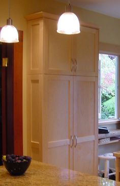 a kitchen with an island and two lights hanging from it's ceiling above the counter