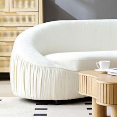 a white couch sitting next to a wooden table on top of a rug covered floor