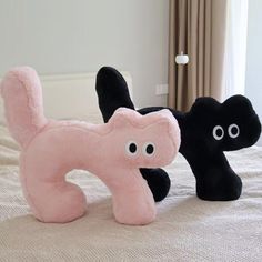 two black and pink stuffed animals on a bed