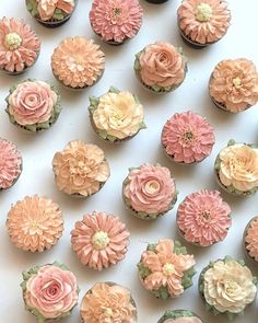 cupcakes decorated with pink and yellow flowers are arranged in rows on a white surface